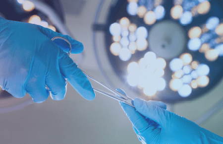 Surgeon passing over surgical tool and surgical light in background