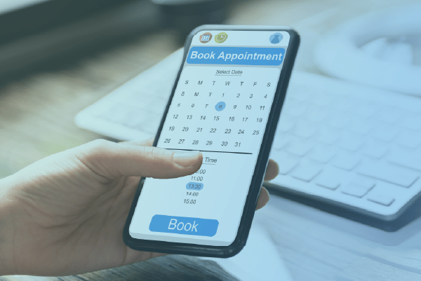 Hands holding a cell phone displaying a calendar for booking an appointment