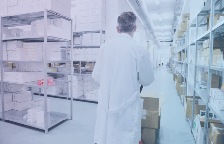 Pharmacist walking alongside shelves of medication