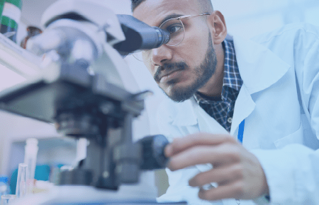 Scientist in lab coat looking at microscope
