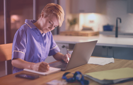 Woman working on laptop and taking notes on notepad