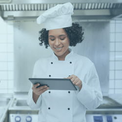 Chef smiling in kitchen while using a tablet