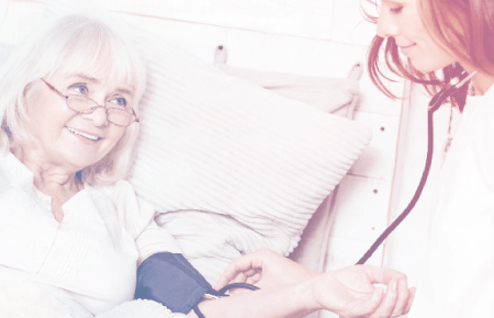 Young female nurse taking elderly womans blood pressure