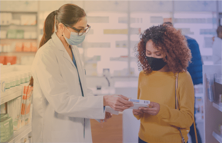 Pharmacist looking at drugs with customer in pharmacy