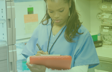 Nurse looking at clip board in stock room
