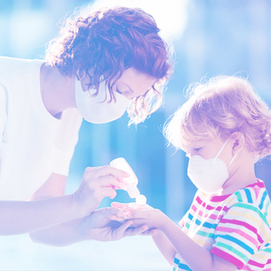 Mother giving hand sanitizer to child.